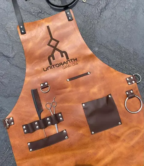 Tan leather apron with an engraved logo and dark accessories